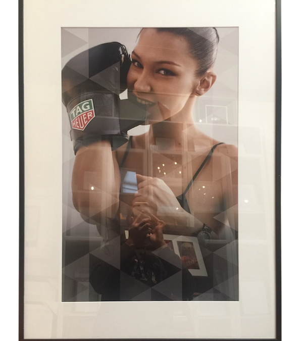 A promotional photo for TagHeuer framed in a narrow box frame with mat board surround and plexiglas.
