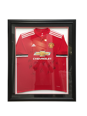 A signed Manchester United jersey framed in a black timber frame with double mat board surround of team colours.