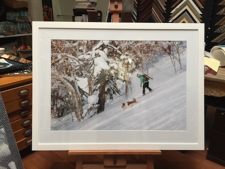 A snowboarding photograph printed by Mahoneys framed in a white timber frame with a mat board surround and UV glass front.