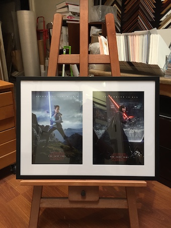 A multi opening black timber box frame with 2 Star Wars movie posters framed with a white mat board and glass.