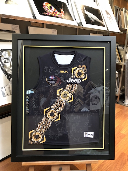 An Indigenous round Richmond Tigers footy jumper framed in a black box timber frame with double mat boards and glass.