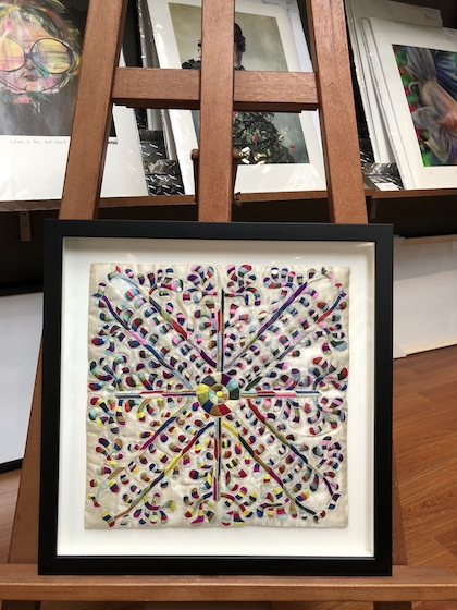 A colourful tapestry framed in a black box timber frame, floated on a white mat board with a spacer and glass.