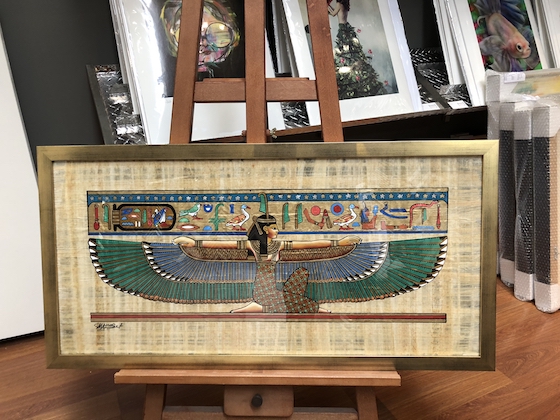 An Egyptian papyrus framed in a gold frame with glass.