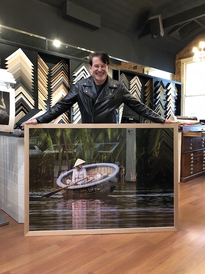Greg Mahoney with a large photographic print framed in a wide Tasmanian oak frame with glass.