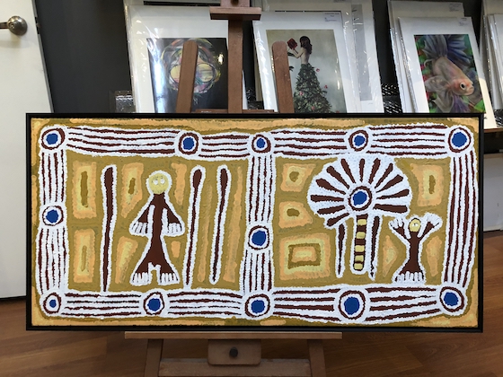 A large Aboriginal artwork stretched and framed in a black floater frame.
