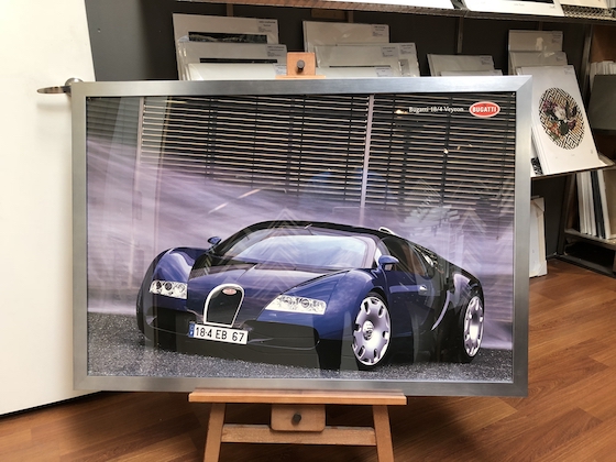 A photographic car print framed in a silver metallic wooden frame with glass.