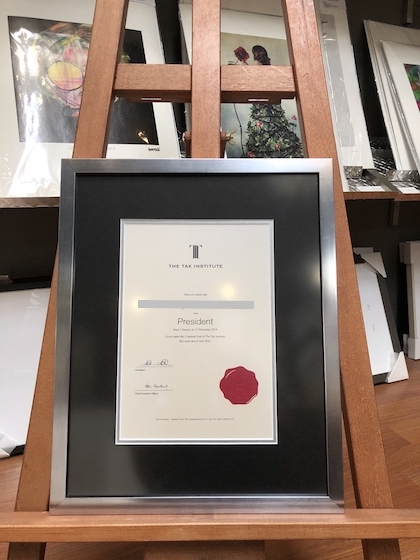 A Tax Institute certificate framed in a wooden metallic frame with a double mat board surround and UV glass.