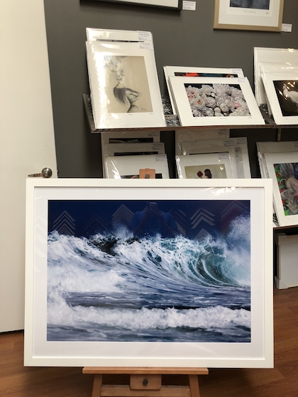 A seascape print framed in a white timber frame with a white mat board and acrylic front.