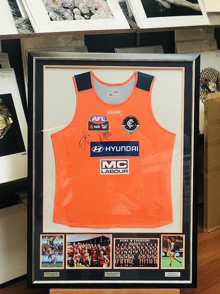 An AFLW womens Carlton jersey framed in a black and silver frame with multiple photos, double mat board surround and silver plaques