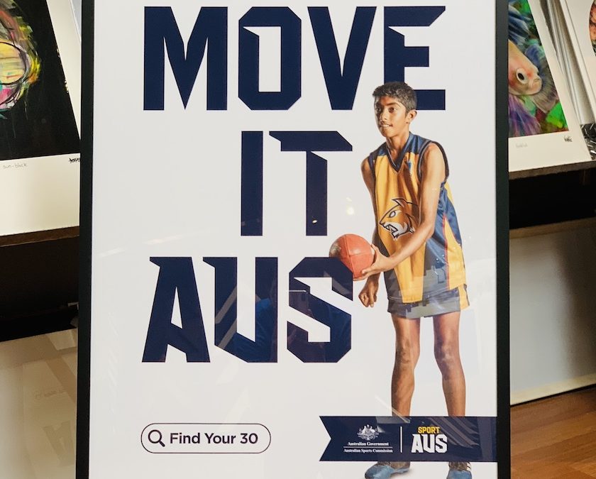 An AFL Sport Aus promotional print part of the Move It Aus campaign framed in a black box frame with glass.