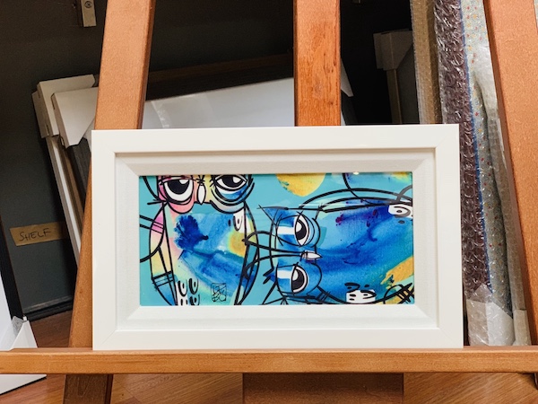 A small original painting of owls framed in a white timber frame.