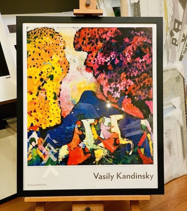 A colourful Kandinsky poster purchased from the Guggenheim museum framed in a black timber frame with glass.