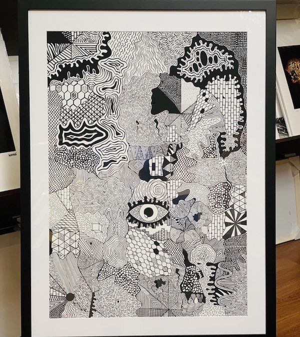 A black and white print framed in a black timber frame with glass.