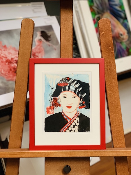 A print framed in a red frame with a white mat board surround and glass.