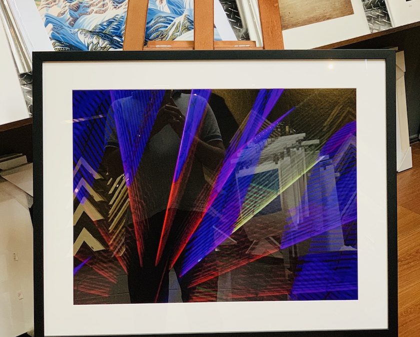 An Abstract photograph framed in a black timber frame with a white mat board surround and glass.