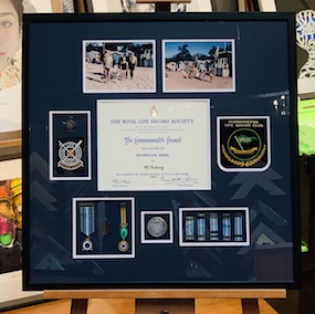A collage of memorabilia of our clients fathers Royal Life Saving photos and badges. We framed the memorabilia in a black frame with a double mat surround and UV glass