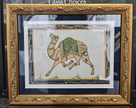 This original camel artwork showcases the intricate beauty and long history of this majestic creature. The piece is framed in a luxurious gold ornate frame that complements the delicate details of the artwork and the two contrasting mats, blue and white, completes the look by accentuating the artwork’s colours.